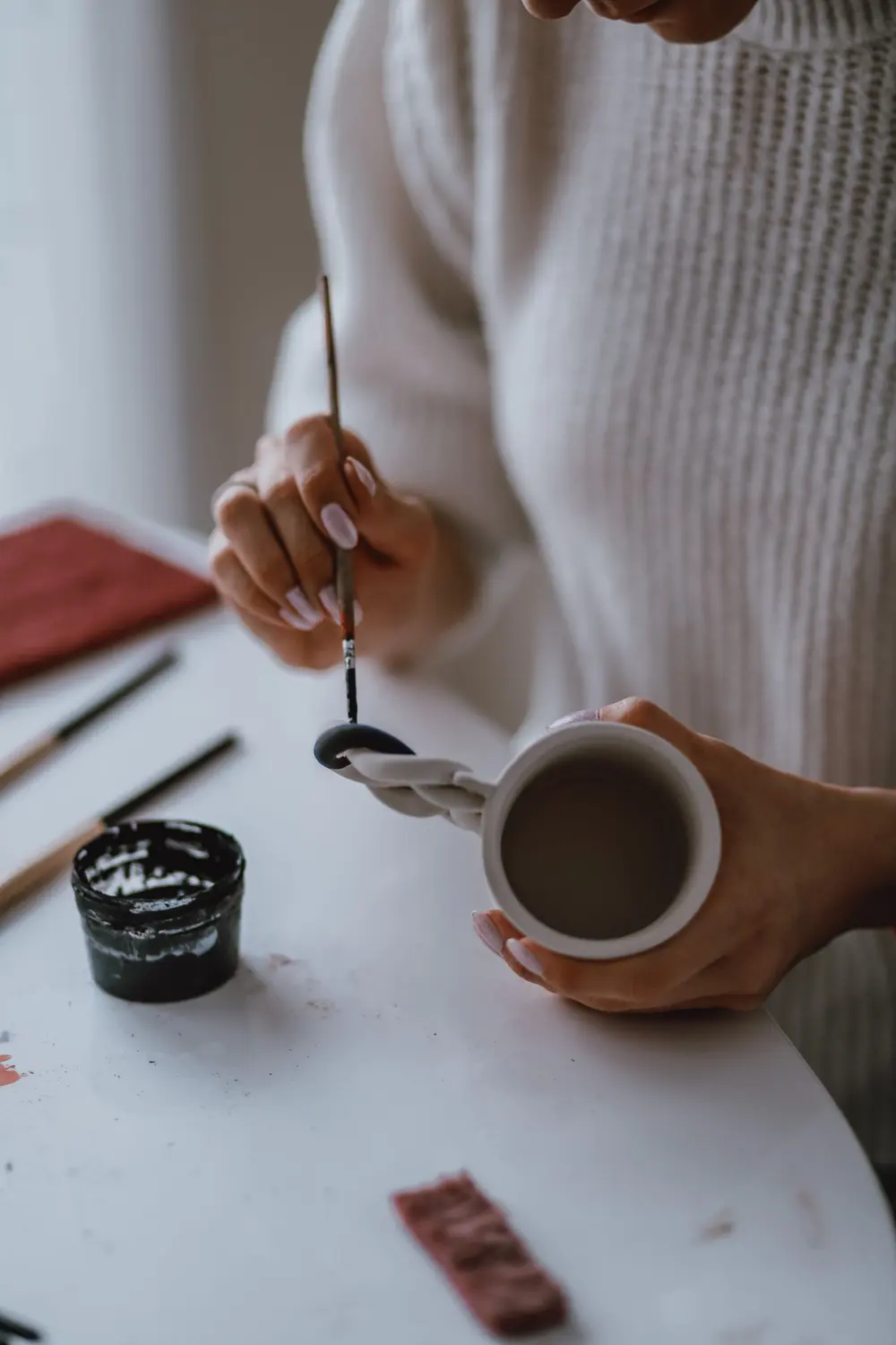 Manos pintando una taza con un pincel, el arte detrás de las tazas personalizadas en San Cristóbal