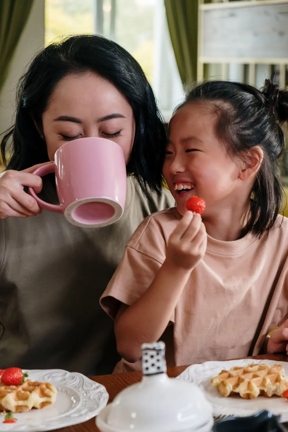 Madre e hija riendo mientras toman en una taza rosada, tazas personalizadas para el día de la madre en San Cristóbal